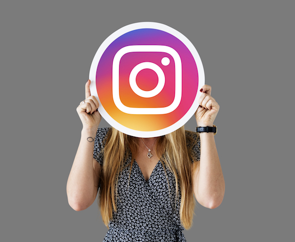 Girl holding Instagram logo in front of face. 