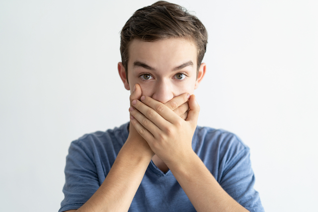 Boy covering mouth with hands to create a mask to prevent brain freeze. 