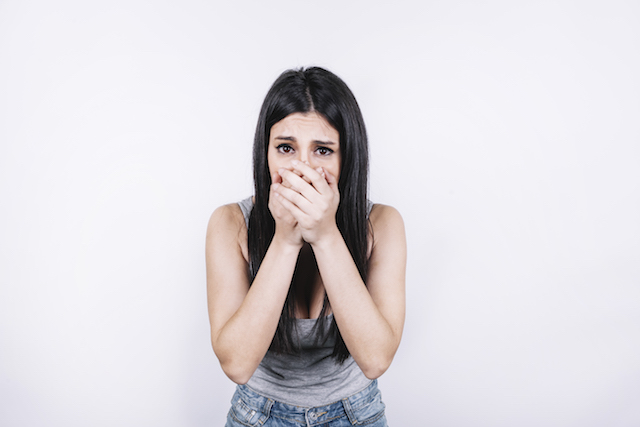 scared woman covering her mouth, represents nightmares with all your teeth falling out.