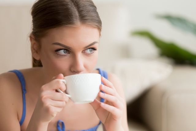Woman drinking out of a mug.