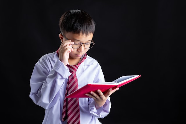a child reading while wearing adult work clothes.