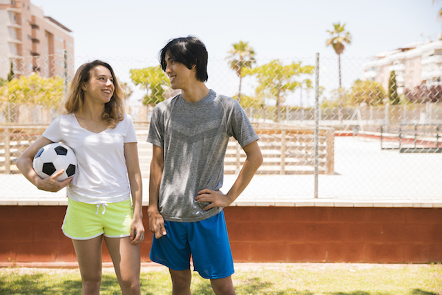 woman and man smiling holding a soccer ball.