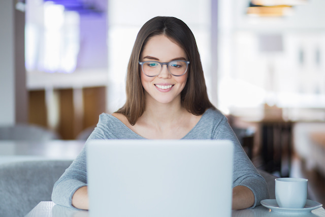 woman wearing blue light glasses while working on a computer to be productive.