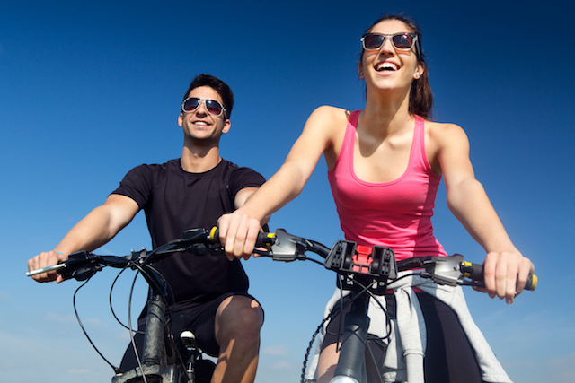 woman and man biking and smiling enjoying sports.