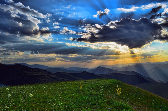 a beautiful meadow with mountains in the background, and sun coming through the clouds as if it were heaven, one of the verbs on the list.