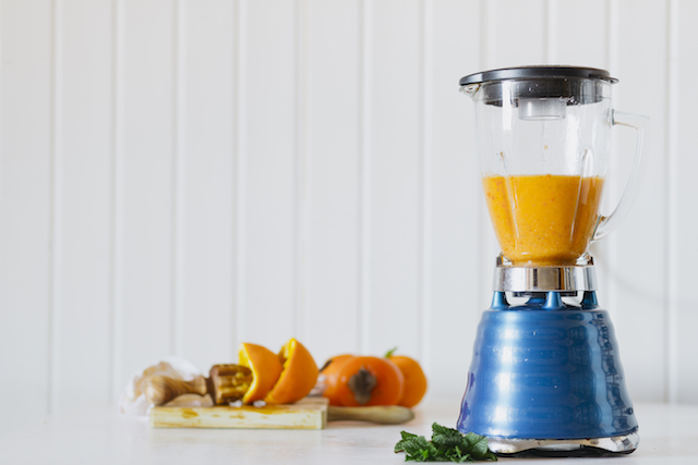 a blender with an orange smoothie inside. 