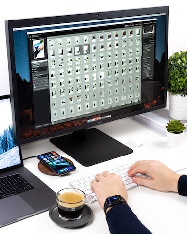 person working on a computer, while also having a laptop and phone screen open. 