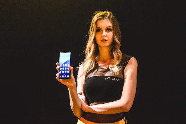 woman looking serious, holding a phone and showing screen to camera. 