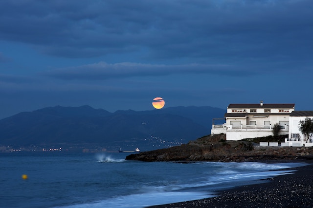 a moon over the water, showing the tides on a beach.